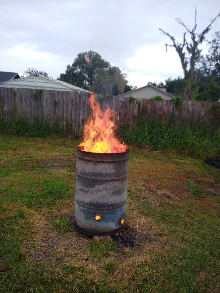 A burn barrel burning in a backyard, providing an efficient and practical solution for waste disposal and emergency heating. Perfect for preppers looking for sustainable outdoor fire options.